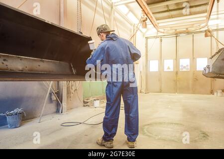 Varnisher in Industrial Metal Factory Malerei eine grosse Schaufel Stockfoto