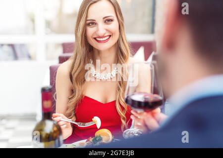 Paar Toasting mit Rotwein in romantischen Restaurant Blick auf einander Stockfoto