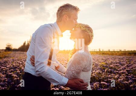 Bräutigam küsst seine Braut während einer romantischen Hochzeit im Dorf in einer romantischen Umgebung Stockfoto