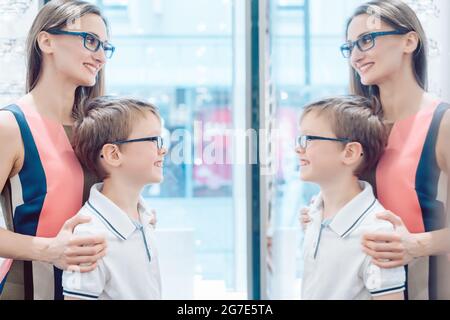 Mutter und Sohn testen neue Brille im Spiegel in Optiker store Stockfoto
