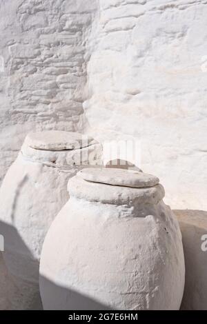 Keramik Töpfe, griechische pithari bedeckt mit Stein gemalt weiß im Freien in einem Haus auf Sifnos Insel, Griechenland, Kykladen. Handgemachte Keramik Tradition Stockfoto