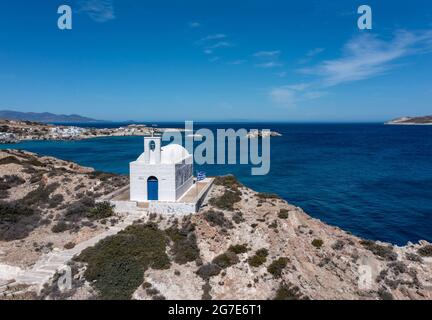 Griechenland Kimolos Insel, Kykladen. Felsige Landschaft, weiße kleine Kirche am Hafen von Psathi, Luftdrohnenansicht. Ruhige Ägäis, blauer Himmel im Hintergrund. Sommer h Stockfoto