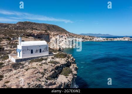 Griechenland Kimolos Insel, Kykladen. Weiße kleine Kirche bergauf am Hafen von Psathi, Blick auf die Drohne. Felsige Landschaft, ruhige Ägäis, blauer Himmel im Hintergrund. S Stockfoto