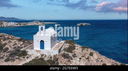 Weiße kleine Kirche auf der Insel Kimolos, Hafen Psathi, Luftdrohnenansicht. Felsige Landschaft, ruhige Ägäis, blauer Himmel im Hintergrund. Griechenland Kykladen. Sonniges wlan Stockfoto