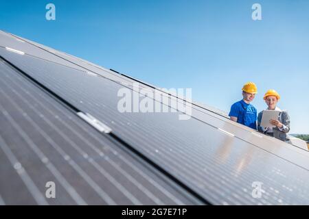 Arbeiter und Investor in Solarkraftwerk zeigt auf die Sonne Stockfoto