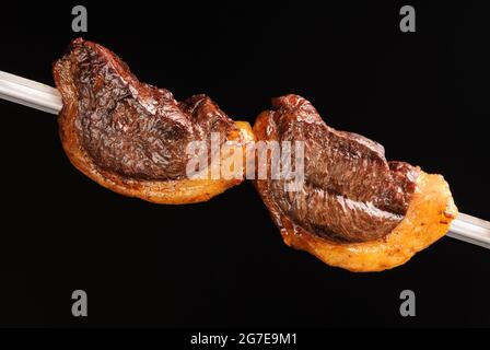 Grillsteak auf Spieße auf schwarzem Hintergrund. Brasilianische Gastronomie. Stockfoto