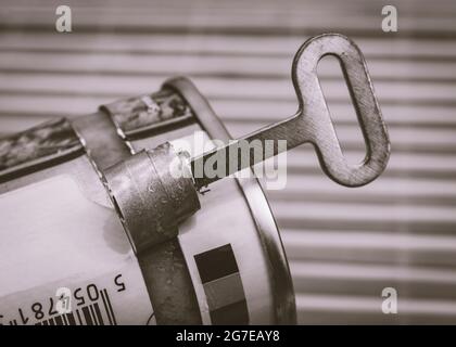 Monochromer Zinnöffner/Dosenöffner bei einem ASDA-Mittagessen in Fleischdose. Konzept für die Konservierung von Lebensmitteln, Öffnen einer Dose von Würmern. Stockfoto