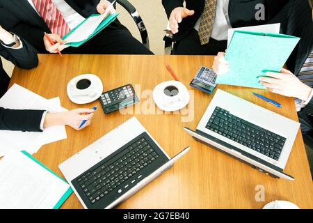 Vier Personen diskutieren oder verhandeln einen Vertrag – und trinken dabei einen Kaffee Stockfoto