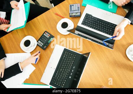 Vier Personen diskutieren oder verhandeln einen Vertrag – und trinken dabei einen Kaffee Stockfoto