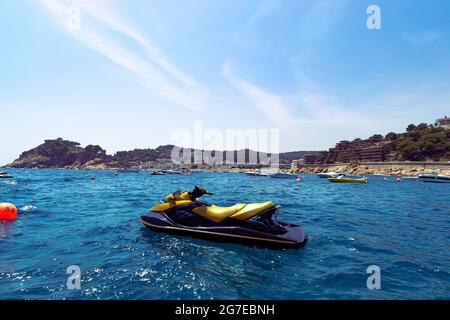 Aufnahme eines welligen Meeres mit einem Jetski vor dem Hotel und vielen Booten im Hintergrund der Berge von Tossa de Mar Stockfoto