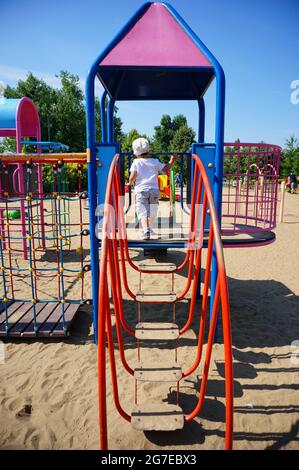 POZNAN, POLEN - 19. Jul 2017: Ein kleiner Junge, der auf einer Ausrüstung mit Stufen auf einem Spielplatz im Jan Pawla Park läuft Stockfoto