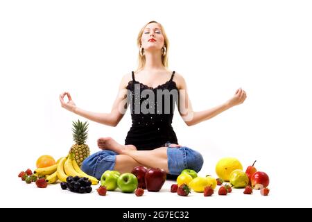 Essen, Obst und gesunde Ernährung - blondes Mädchen sucht Aufklärung inmitten einer Menge Obst Stockfoto