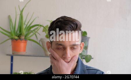 Nahaufnahme eines Mannes, der eine Denim-Jacke und ein pinkes T-Shirt trägt und zu Hause vor Pflanzen steht Stockfoto