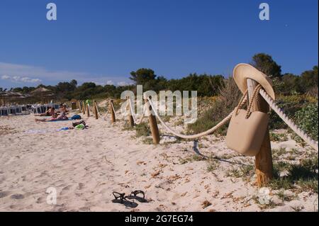 Holzzaun mit einer Tasche und einem Hut, der darauf am Strand hängt Stockfoto