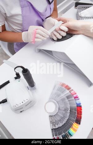 Vertikale Draufsicht, zugeschnittene Aufnahme des Manikuristen-Tisches mit Nagellack-Palette und Nagelbohrer Stockfoto