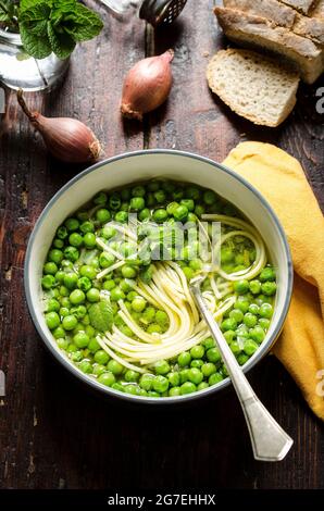 PEA-Suppe mit Pasta in einer weißen Schale auf einem Holztisch Stockfoto