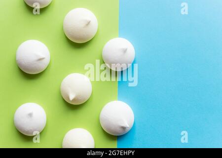 Muster mit zarten hellgrünen, weißen, gelben und rosa Baiser-Keksen. Baeringues Stockfoto