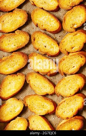 Scheiben frisch gebackenes Crostini-Brot auf Backpapier Stockfoto