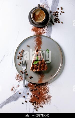Scheibe hausgemachtes glutenfreies Tiramisu traditionelles italienisches Dessert mit Kakaopulver bestreut, dekoriert mit Kaffee, Minzblättern und Kaffeebohnen-Ove Stockfoto