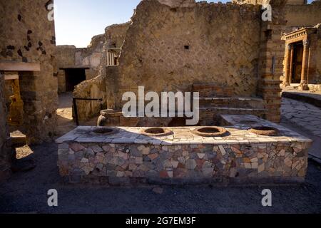 Thermopolium oder Taberna (Köchin) in Ercolano - Herculaneum, alte römische Stadt, die durch den Ausbruch des Vulkans Vesuv oder Vesuv zerstört wurde. Stockfoto