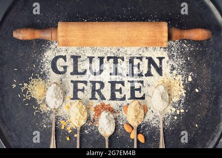Glutenfrei in Mehl auf Jahrgangsbackblech, Nudelholz und Löffel aus verschiedenen glutenfreien Mehl (Mandelmehl, Buchweizenmehl, Reismehl, Stockfoto