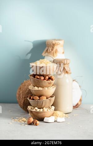 Vegane Milch auf pflanzlicher Basis ohne Milchprodukte in Flaschen und Zutaten auf blauem Hintergrund. Alternativer laktosefreier Milchersatz Stockfoto