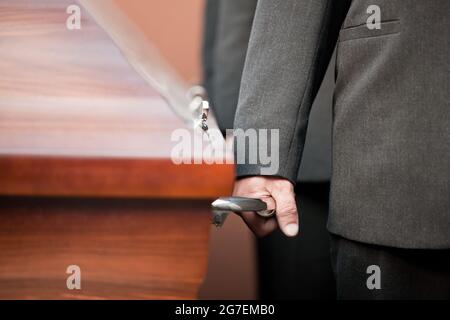 Religion, Tod und Dolor - Sarg Träger tragen die Schatulle bei Beerdigung, Friedhof Stockfoto