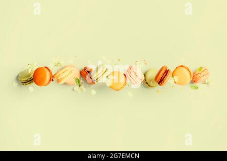 Französische Makronen oder Makronen in Vintage-Pastellfarben, die auf hellgrünen Hintergrund fallen. Macaron Süßigkeiten Stockfoto