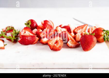 Erdbeeren in Scheiben geschnitten auf einem weißen Brett Stockfoto