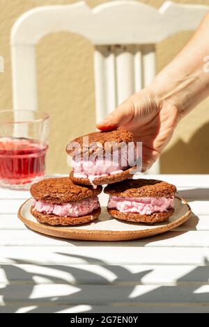 Weibliche Hand hält ein Brownie-Cookie-Eis-Sandwich Stockfoto