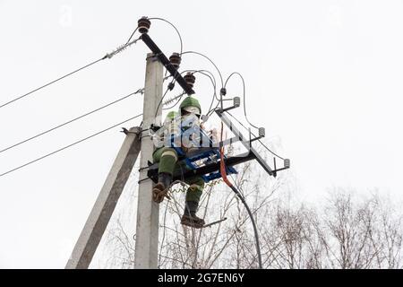 Reparatur von elektrischen Netzen. Elektroinstallateur bei der Arbeit an der Stange. Elektriker klettern auf elektrische Pole, um Stromleitungen zu installieren und zu reparieren Stockfoto