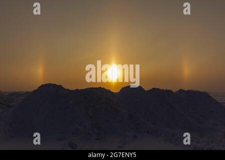 Sonniger optischer Halo-Effekt am frühen Morgen auf dem Hintergrund von Schneemügeln. Das Konzept der Untersuchung der Umwelt. Stockfoto