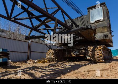 Alter Raupenkran auf einer Baustelle. Baggerspuren auf der Baustelle mit Schmutz bedeckt Stockfoto