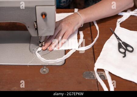 Nähen von medizinischen Schutzmasken mit eigenen Händen auf einer Nähmaschine, Mangel und Mangel an persönlicher Schutzausrüstung Stockfoto