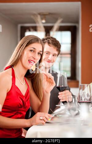 Porträt einer glücklichen Frau Essen mit Mann sitzt hinter Getränk Stockfoto
