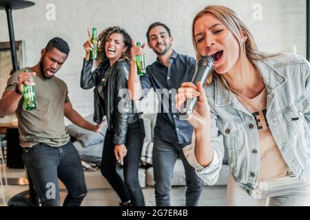 Gruppe von Freunden, die zu Hause Karaoke spielen. Stockfoto