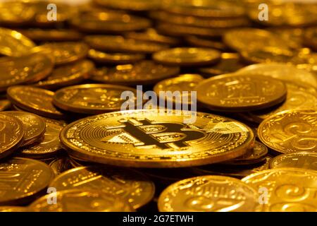 Goldkryptowährung Bitcoin vor dem Hintergrund vieler anderer Goldmünzen in weichem Licht. Neues Konzept des steigenden Werts der basierten Blockchain-industr Stockfoto