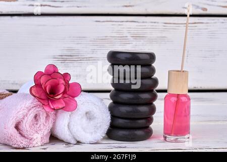 Stapel von Spa-Steinen und Handtücher mit Blume und Lotion. Stockfoto