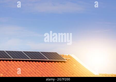 Solarpaneele auf einem Dach bei Sonnenuntergang. Saubere Energie modernes Haus- oder Firmenkonzept. Stockfoto