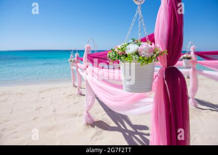 Setup von Hochzeit ehe Gang mit Vorhängen und Bogen auf Sandy Tropical Beach Paradise Ocean Hintergrund zu öffnen. Stockfoto