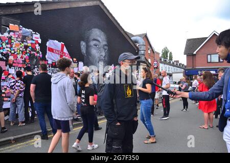 Der Straßenkünstler Akse wird vor dem riesigen Wandgemälde des Manchester United-Spielers Marcus Rashford in Withington, Manchester, England, Großbritannien, interviewt, das er malte. Das Wandbild wurde nach dem Verlust der englischen Fußballeuropéen20 am 11. Juli 2021 mit missbräuchlichen Graffiti verwüstet. Das Wandbild wurde von dem in Frankreich geborenen Straßenkünstler Akse an der Wand des Coffee House Cafe in der Copson Street geschaffen. Marcus Rashford ist ein Fußballspieler von Manchester United. Akse reparierte das beschädigte Wandbild bis zum 13. Juli 2021 vollständig. Bilddatum: 13. Juli 2021. Stockfoto