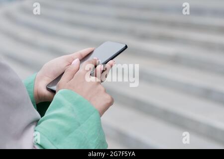 Nicht erkennbare junge Frau, die im Treppenhaus steht und das Smartphone in Bewegung benutzt Stockfoto