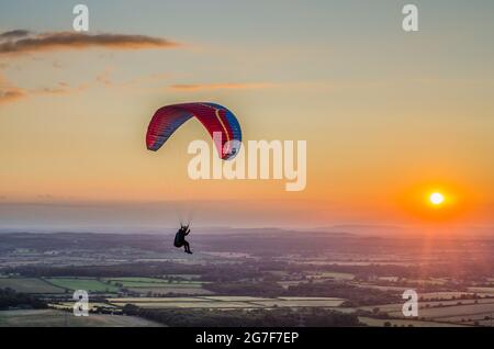 Devils Dyke, Brighton, East Sussex, Großbritannien. Juli 2021. Wind aus nördlicher Richtung bringt Gleitschirmflieger zu den herrlichen South Downs nördlich von Brighton. Eingleisiger Gleitschirm über die neblige Landschaft. Kredit: David Burr/Alamy Live Nachrichten Stockfoto