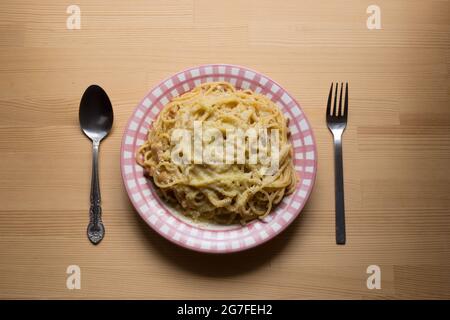 Draufsicht auf einen Teller mit einer Carbonara-Pasta, mit Löffel und Gabel. Stockfoto