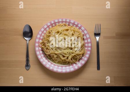 Draufsicht auf einen Teller mit einer Carbonara-Pasta, mit Löffel und Gabel. Stockfoto