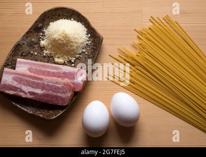 Auf einem Schneidebrett ausgestellte Rohwaren zur Zubereitung einer Carbonara-Pasta, einem traditionellen Gericht Roms. Stockfoto