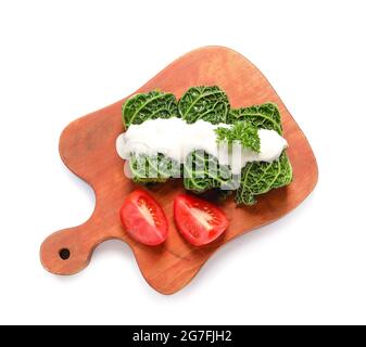 Brett mit gefüllten Kohlblättern, Sauerrahm und geschnittenen Tomaten auf weißem Hintergrund Stockfoto