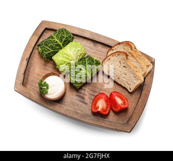 Brett mit gefüllten Kohlblättern, Sauerrahm, Brot und geschnittenen Tomaten auf weißem Hintergrund Stockfoto