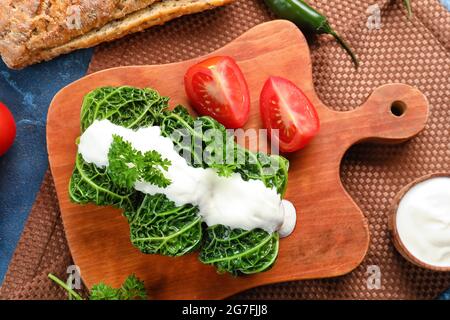 Tafel mit gefüllten Kohlblättern, Sauerrahm und Tomaten auf dem Tisch Stockfoto