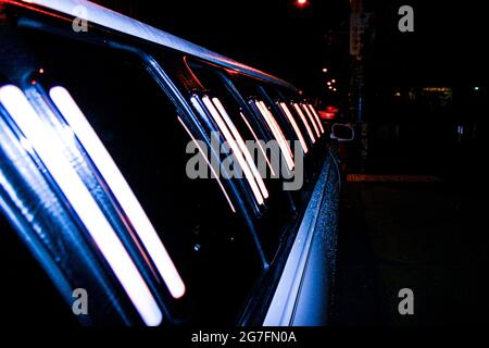 Eine Long Stretch-Limousine, die in einer regnerischen Nacht mit Wassertröpfchen bedeckt ist Stockfoto